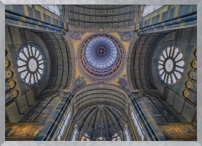 An upward-looking view of the highly ornate vaulted ceiling of a grand cathedral, featuring a central glass dome, large rose windows, and intricate gold and blue details, all framed in silver. Poster
