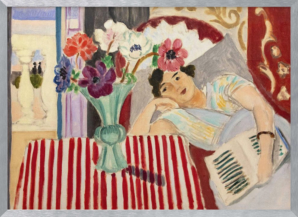 A Fauvist-style painting by Henri Matisse depicting a woman in a colorful blouse reclining with a book. Beside her is a table with a bold red-and-white striped cloth holding a light green vase with red, purple, and white anemone flowers. Print