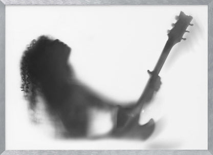 A framed, black and white photograph showing the blurry silhouette of a rock guitarist with long curly hair, head thrown back in passion while holding an electric guitar against a stark white background. Poster