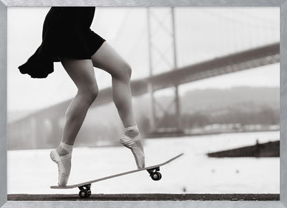 A black and white photograph of a ballerina's legs in a black dress, balancing en pointe on a skateboard with a blurred bridge in the background. Artwork