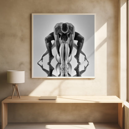 A framed black and white studio photograph of two dancers, a man and a woman, creating a symmetrical pose. The muscular man is positioned over the woman who is curled up beneath him. Their limbs are extended and reflected on the mirrored surface below, forming an abstract and powerful composition. Decor