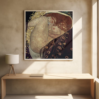 A print of Gustav Klimt's 1907 painting, 'Danaë'. The artwork depicts a sleeping, nude woman with vibrant red hair curled into a fetal position, receiving a shower of golden rain. The style is characteristic of Art Nouveau, with rich, decorative patterns on surrounding fabrics against a dark, star-like background, all within a light wood frame. Wall Art
