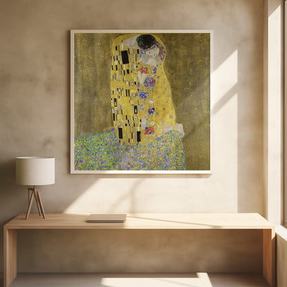 A framed print of Gustav Klimt's famous painting, 'The Kiss'. It features a couple in a passionate embrace, adorned in ornate, patterned golden robes. They are kneeling on a vibrant bed of flowers against a shimmering, textured gold background. Print