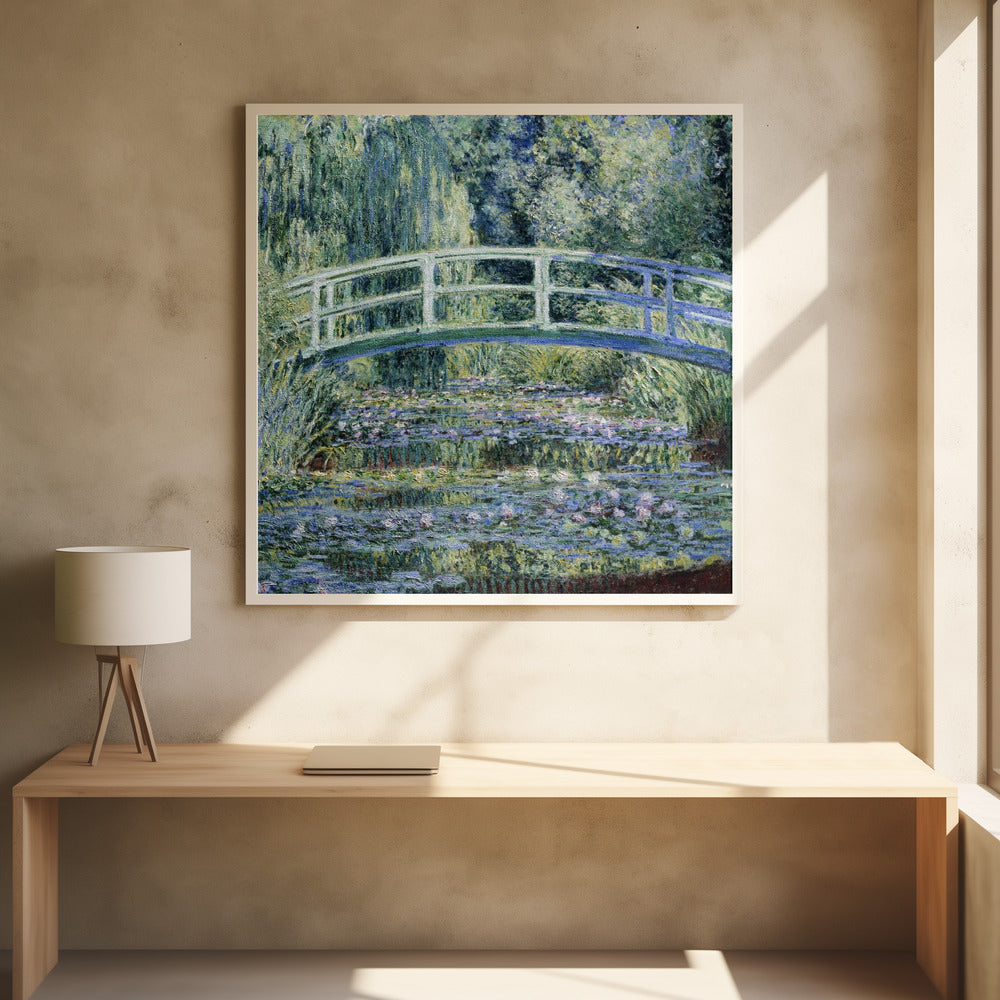An Impressionist painting by Claude Monet, 'The Water Lily Pond', in a light wood frame. A pale green Japanese footbridge arches over a tranquil pond filled with pink and white water lilies, reflecting the lush green and blue foliage of weeping willows that surround it. Poster